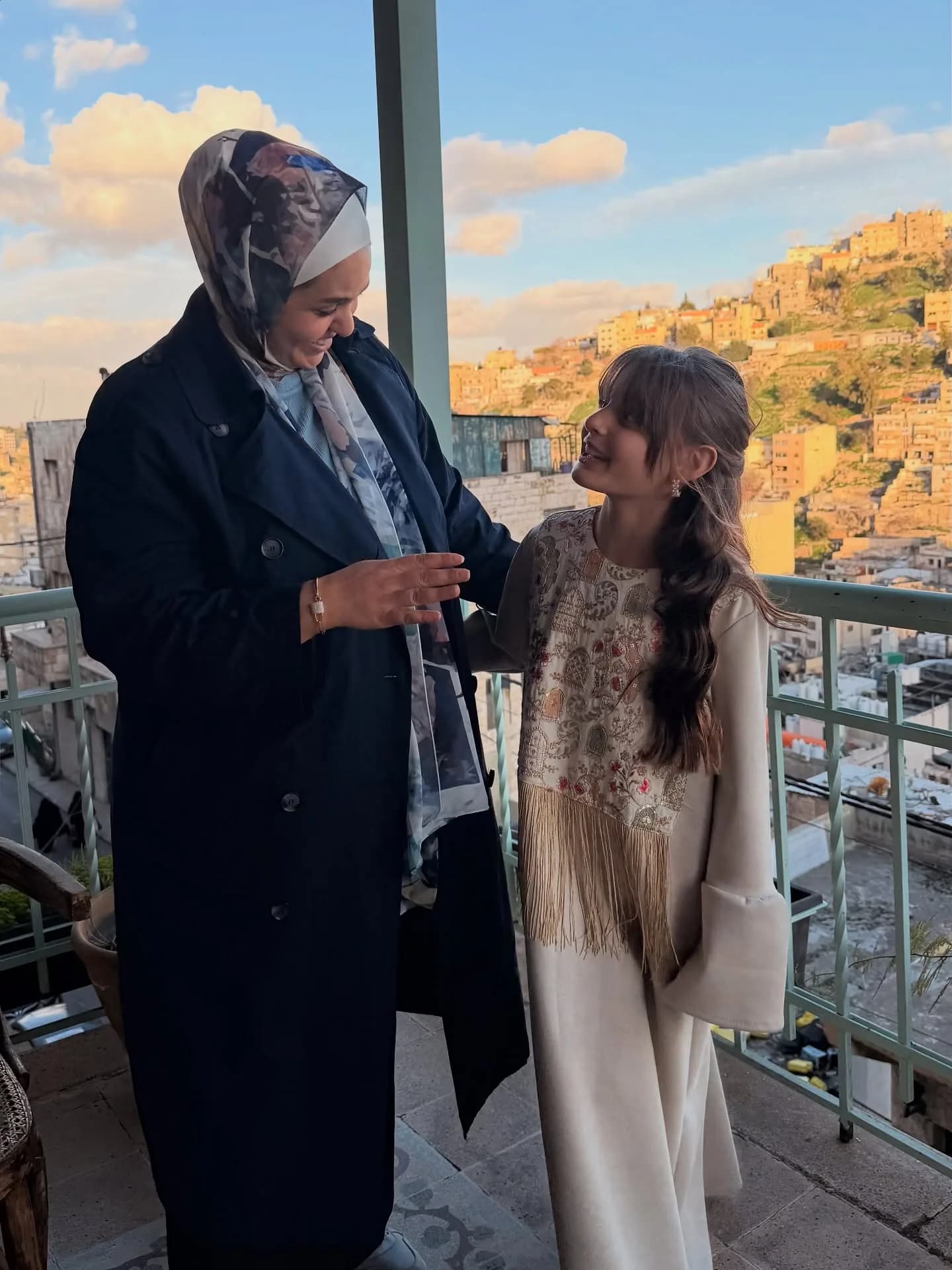 A mother and daughter wearing RAYHAN on a balcony overlooking Amman at sunset
